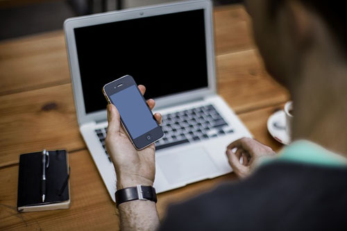 person with cell phone and laptop